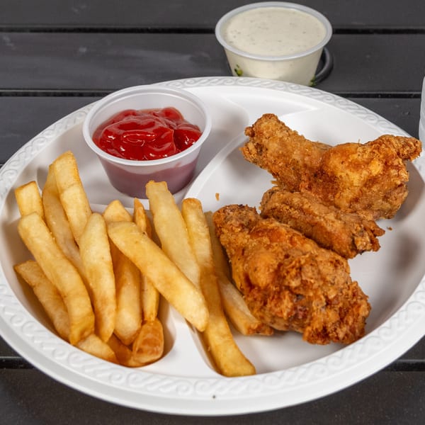 Fried chicken wings and french fries with ketchup and ranch dressing on a white plate.