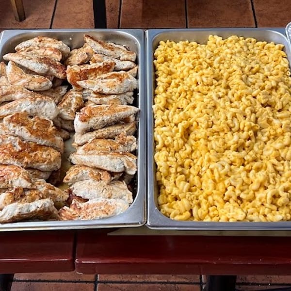 Four large trays of buffet food: macaroni and cheese, grilled chicken, and green beans.